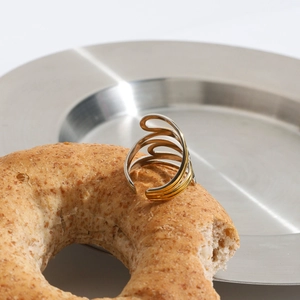 Artistic close-up of a dual-tone spiral layered ring on a minimalist steel tray