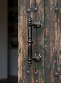 Close-up of vintage black cast iron cabinet handle on distressed rustic wooden door