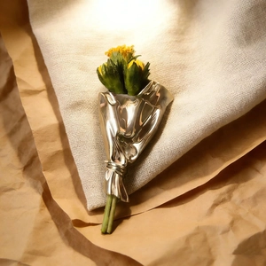 Detail of silver bouquet brooch with yellow flowers on rustic linen and craft paper