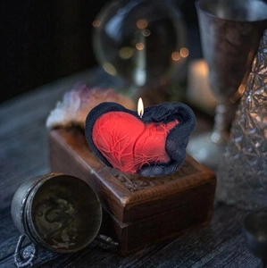 Artistic candle detail showing a red heart with a black snake on a vintage wooden box