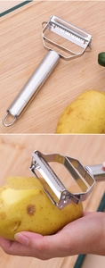 Close-up of stainless steel dual-blade peeler showing shredding and peeling on wood board