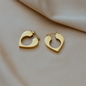 Detail of 18K gold-plated heart-shaped hoop earrings on soft satin fabric background