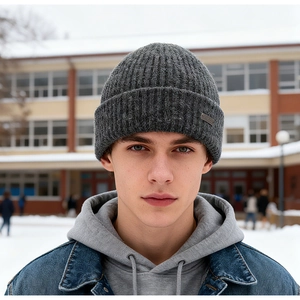 Close-up of thick dark grey cable knit beanie featuring a metallic side logo detail