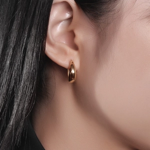 Macro view of gold teardrop hoop earrings worn to show smooth polished metal finish