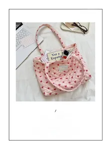 Top view of pink quilted tote bag with heart patterns holding laptop and daily items
