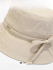Vue détaillée du chapeau cloche beige montrant la texture du tissu, le nœud et le logo doré