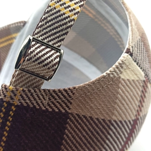Detailed macro of a plaid baseball cap featuring a silver metal adjustable buckle strap