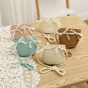 Detail of colorful hand-woven straw crossbody bags with lace bows and zipper closure