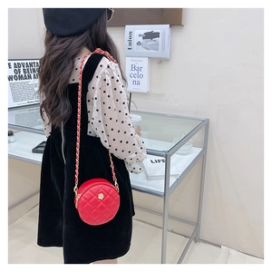 Model view showing red round quilted mini chain bag for kids with metallic flower detail