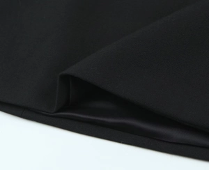 Dettaglio della trama del tessuto twill nero e delle cuciture fini sull'orlo dell'abito