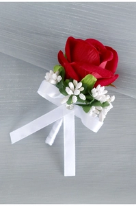 Detail of red velvet rose boutonniere with white ribbon and green leaves for wedding