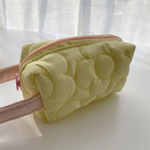 Detail of floral quilted cosmetic bag in cream yellow with pink zipper and soft handle