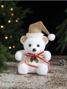 Detail of white flocked snowman bear with burlap hat and red bells in a warm Christmas setting