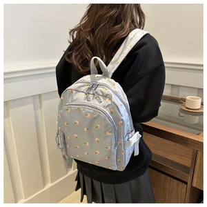Detail view of stylish blue floral backpack with double zippers and adjustable buckles