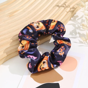 Detail of Halloween scrunchie with pumpkin and bat prints on purple silk-like fabric