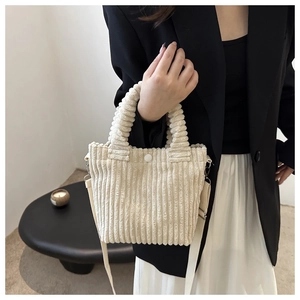 Detail of cream corduroy bucket bag texture with white resin button and shoulder strap