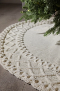 Détail du tapis de sapin de Noël blanc tricoté avec motif de losanges sur parquet