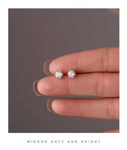 Detailed view of silver six-prong star earrings with cubic zirconia on model's fingers
