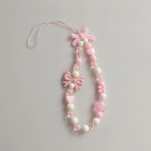 Close-up of pink and white beaded phone charm with bow, heart and bear shapes