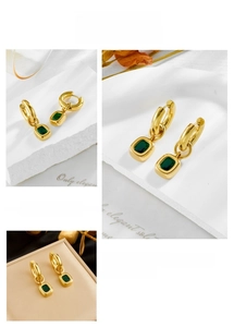 Macro detail of vintage gold hoop earrings with rectangular emerald green gemstone drop