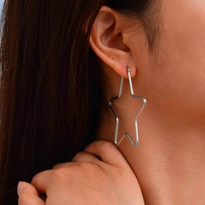 Close-up of a large silver hollow star-shaped hoop earring on a female model