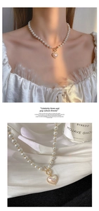 Macro shot of pearl heart necklace with gold T-bar clasp on white satin background