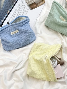 Three-piece set of textured bubble fabric makeup bags in pastel yellow, blue, and green
