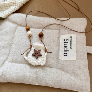 Close-up of hand-woven mini bag pendant necklace with a wooden star and earthy beads