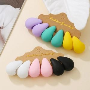 Close-up of six pairs of matte drop-shaped stud earrings in vibrant assorted colors