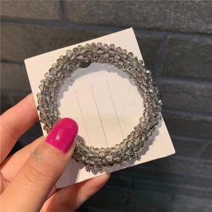 Detailed view of gray beaded elastic hair tie with faceted crystal beads on display card
