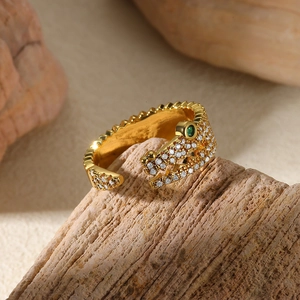Detailed macro shot of golden crocodile ring with pavé zircons and green emerald eyes