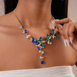 Détail d'un collier floral avec cristaux bleus et pompons goutte d'eau sur un mannequin