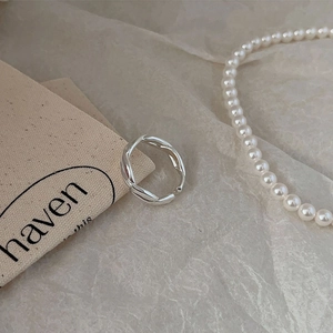 Macro shot of silver twisted braided ring on fabric background with pearls