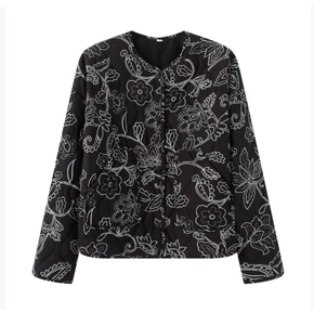 Detail of black quilted jacket featuring intricate white floral embroidery and snap buttons