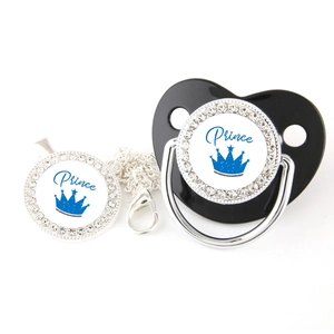 Close-up of black baby pacifier and silver clip with blue Prince crown and crystals