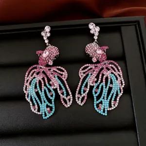 Boucles d'oreilles poisson avec cristaux roses et bleus sur cuir noir luxueux