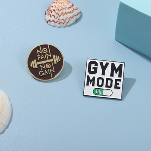 Macro view of GYM MODE and NO PAIN NO GAIN enamel pins with barbell detail