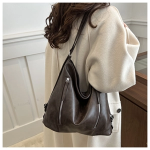 Detail view of large dark brown hobo bag showing faux leather texture and vertical zippers