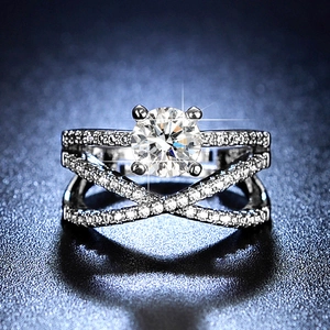 Macro shot of a cross-band silver ring with a large round moissanite in a four-prong setting