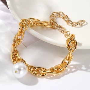 Detailed close-up of Baroque pearl bracelet with chunky gold chain on a ceramic plate