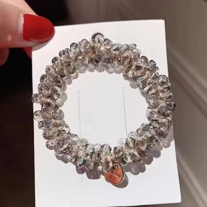Detail of crystal beaded hair tie with rose gold metallic charm and elastic band