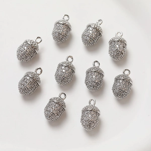 Detailed view of nine silver acorn charms with clear micro-paved sparkling gemstones