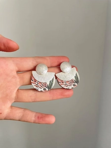 Détail des boucles d'oreilles géométriques argentées avec imprimé désert et texture brossée