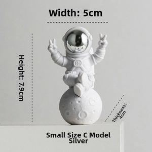 Silver astronaut figurine sitting on moon model, dimensions 5cm wide and 7.9cm high