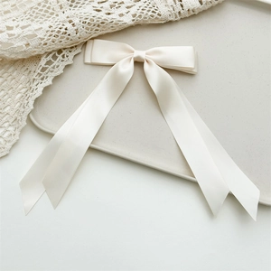 Detailed macro view of the cream white satin ribbon texture and smooth silk finish of the bow