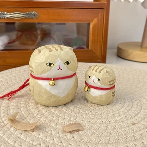 Detail of hand-carved wooden cat ornaments with red collars and golden bells