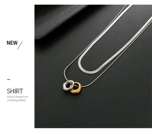 Detail of double-layer interlocking gold and silver ring pendant on flat snake chain