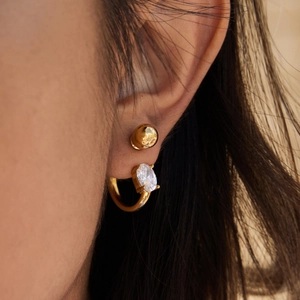 Macro shot of 18K gold plated hoop earrings featuring a large oval cubic zirconia stone