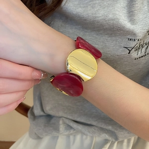 Mannequin portant un large bracelet en résine marbrée et métal doré poli élégant