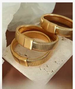Detailed view of three vintage gold Tubogas style expandable bracelets on stone display